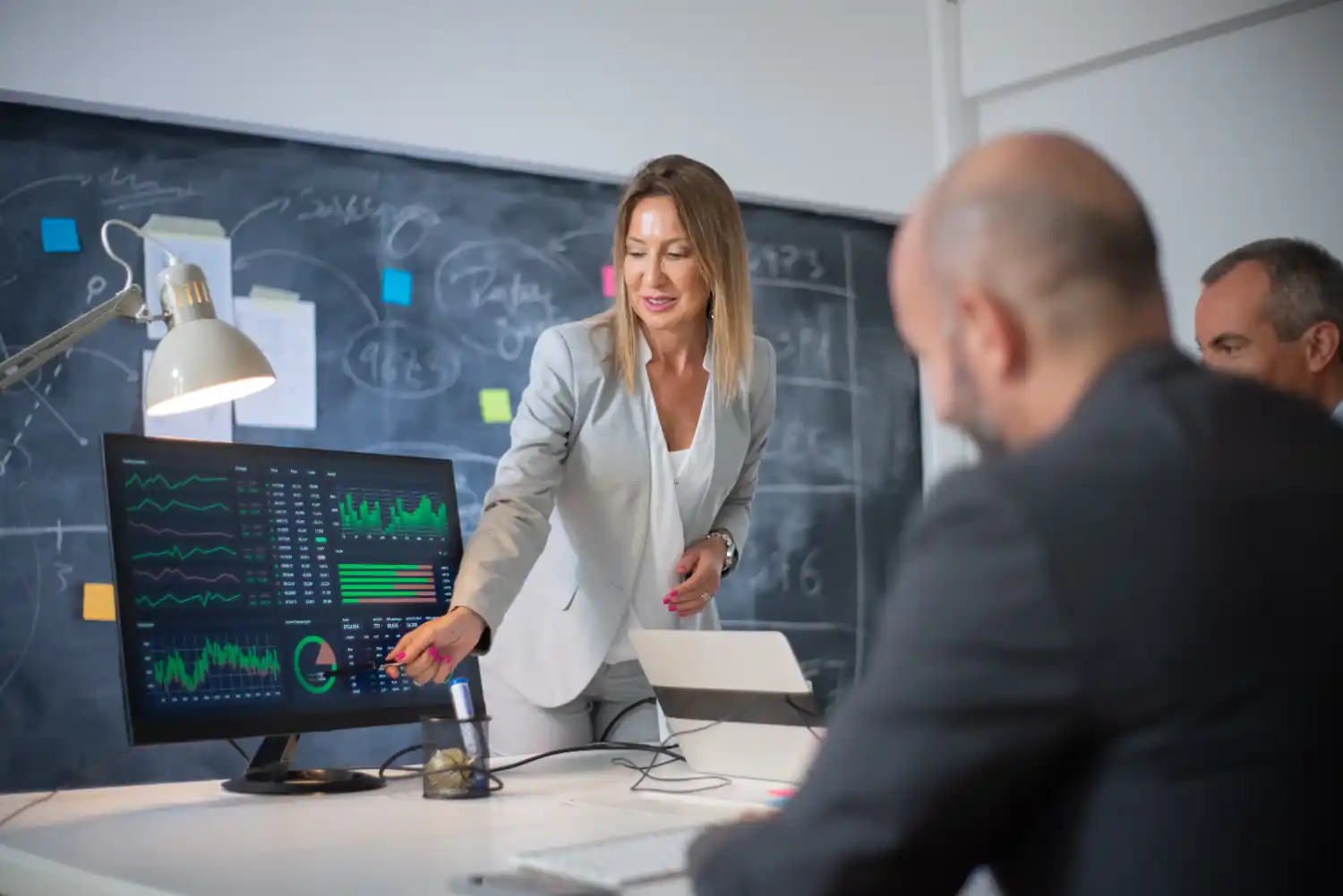 A female team lead shows her team how to properly interpret data present on a screen